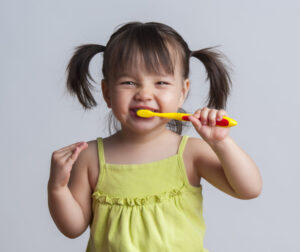 Toddler smiling while brushing her teeth