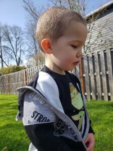 Caleb outside in his backyard with green grass