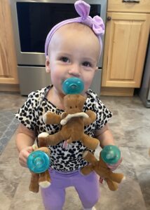 Photo of child with pacifier holding a teddy bear