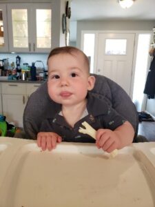 Caleb in a high chair eating celery