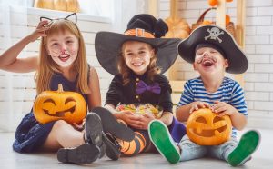 Cheerful children play with pumpkins and candy.