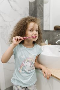 Chica de pelo rizado en pijama se cepilla los dientes