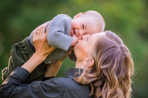 Woman kissing young baby near his mouth