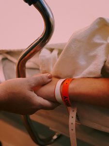 Photo of a child in a hospital bed holding hands with a support person