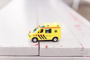 Small yellow toy ambulance sitting on a white wooden surface