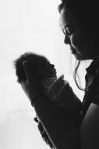 Black and white image of a mother holding her swaddled newborn