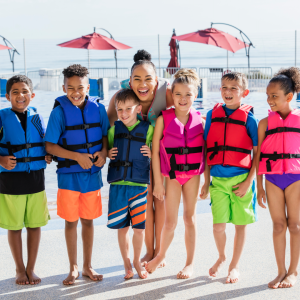 Six children in neon life jackets face the camera smiling