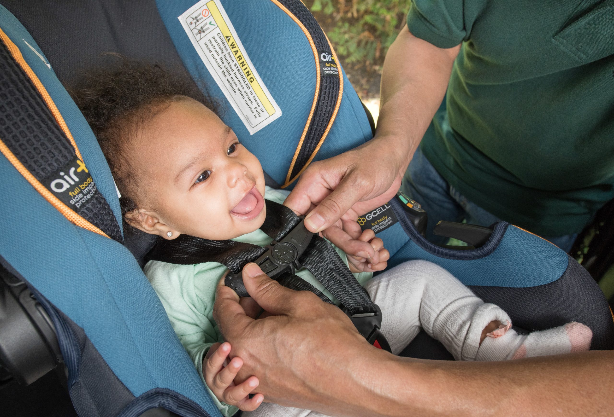 Man buckling happy baby into a rear-facing car seat