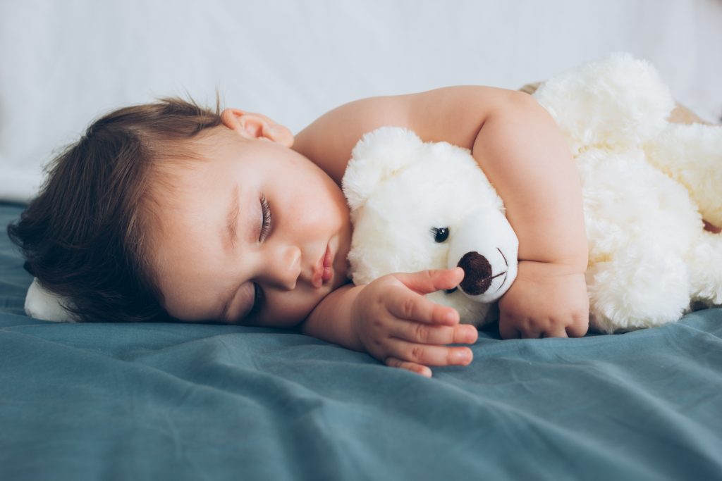 Beautiful baby sleeping with his teddy bear aside, family concept