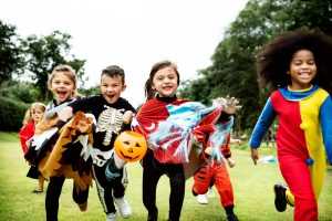 Little kids in costume running on green grass