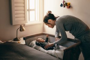 Mom leaning over her baby in a sidecar crib