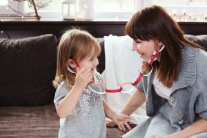 Mother and daughter playing with hand made paper chain, laughing. Cute Christmas lifestyle scene.