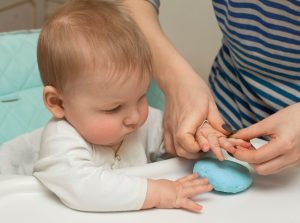 Parent making impression of baby's hand in blue dough