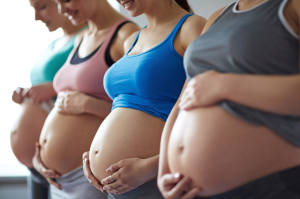 A line of pregnant people showing their bellies.