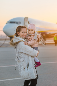 Woman holding toddler in front of a large plane