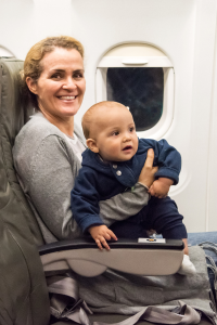 Woman on a plane with a toddler climbing in her lap