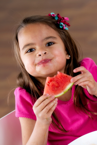 Young girl in a pink shirt eating watermelon