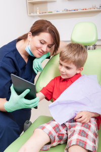 Dentist and child look at tablet in a dentist chair