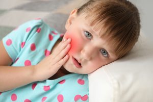 Little girl suffering from toothache at home