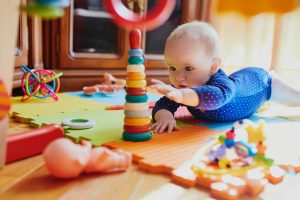 Baby girl playing with toys on the floor.