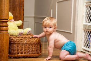 10 month old baby boy in blue cloth diaper crawling at home