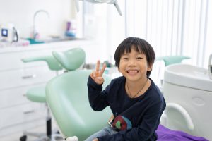 Asian boy smiling as he sits in a dental chair in dental clinic