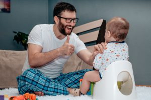 Father supports young child on the potty.