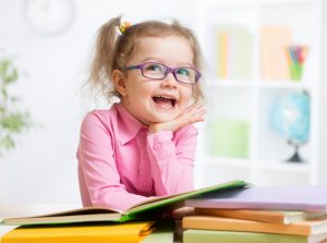 Happy kid reading books and dreaming in room