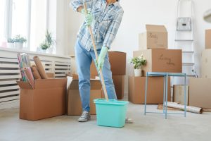 Portrait of happy young woman cleaning new house while moving in.