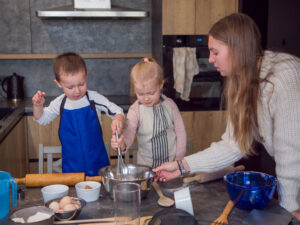 Mother and her children bond while making cookie dough together in a contemporary kitchen.