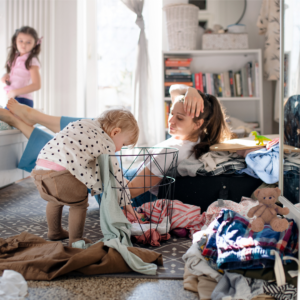 Mom stilling watching baby reach into basket and toss out laundry.