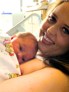 Whitney and her newborn daughter in the hospital smiling at the camera