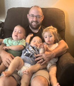 Tony and his three children sitting in a recliner