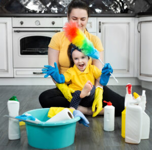 Young woman and her little daughter sit on the floor and have fun cleaning their house