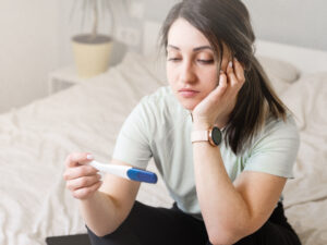 Woman looking at a pregnancy test with a sad expression