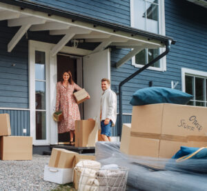 Young Family Moving to Their New Home in Residential Area. Handsome Man Unloading a Cargo Van Full of Cardboard Moving Boxes.