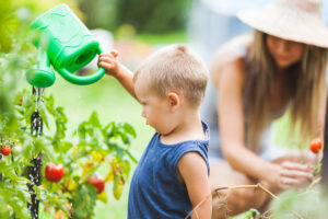 Cute toddler helphing out mom in the garden