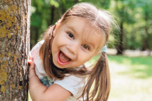 Close-up portrait of an excited little girl laughing in summer park