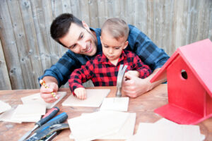Dad and young son doing a birds house project together