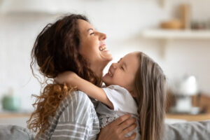 lose up side view overjoyed smiling young mother and daughter hugging and laughing.