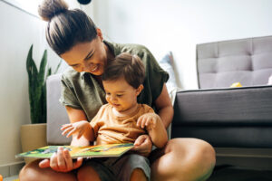 Mom reading a book with baby boy at home.