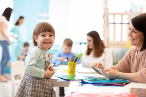 Niños aprendiendo artes y manualidades en el jardín de infantes con la maestra.